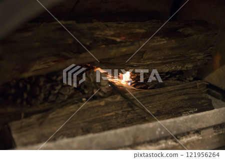 Image of lighting a wood stove with pine cones. 121956264