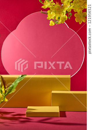 Three golden platforms are arranged on a red surface. A large, flower-shaped crimson cutout forms a backdrop. Branches of bright yellow apricot blossoms. Ideal for a Lunar New Year product ad. 121956521