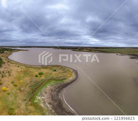 Colorful autumn forest with trees on the shore of a blue lake - top aerial view. Colorful autumn forest with trees on the shore of a blue lake - top aerial view. 121956623