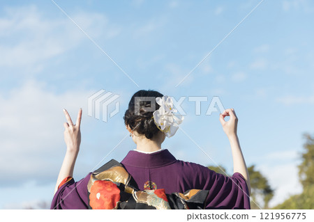 Image of a women's coming-of-age ceremony: A young woman in a kimono showing the number 20 with her hand, view from behind 121956775