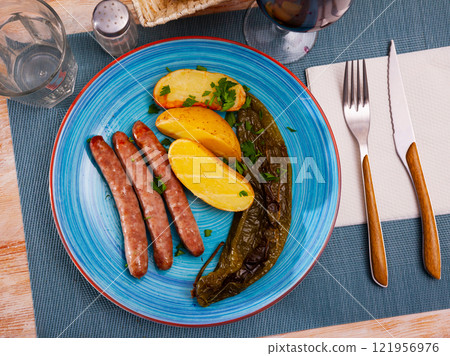 Grilled sausages with potato, pepper and herbs 121956976
