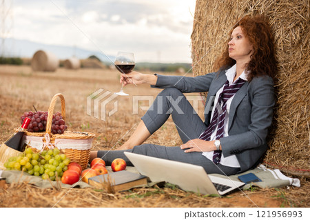 Tired business woman drinking wine during country picnic Tired business woman drinking wine during country picnic 121956993