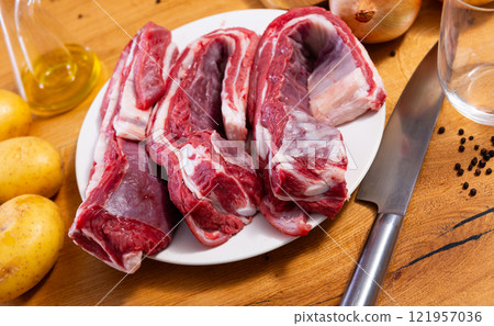 Fresh raw pork ribs with potatoes, onions and black pepper on wooden table Fresh raw pork ribs with potatoes, onions and black pepper on wooden table 121957036
