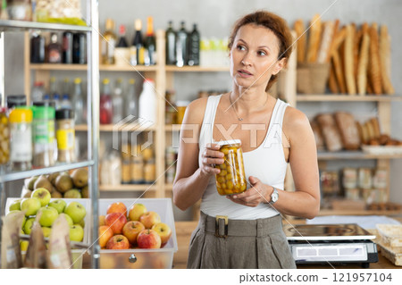 Adult woman choosing olives in grocery store 121957104
