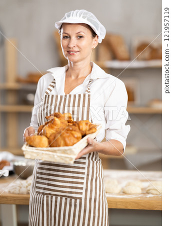 Smiling female baker with basket of croissants Smiling female baker with basket of croissants 121957119
