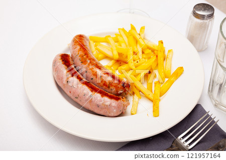 Grilled spicy sausages served with french fries 121957164