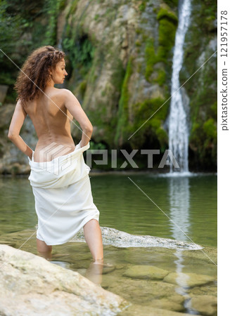 Back view of woman in white dress standing by waterfall Back view of woman in white dress standing by waterfall 121957178