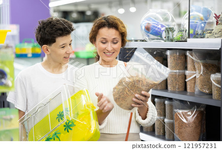 Woman with teenage son selecting food for turtles in pet store 121957231