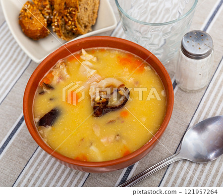 Plate of hearty pea soup with smoked meat served with bread 121957264