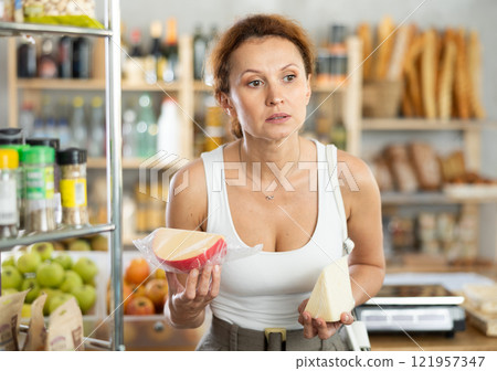 Adult woman choosing cheese in grocery store 121957347