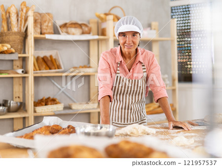 Elderly female baker posing in workshop Elderly female baker posing in workshop 121957537