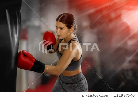 Girl punches and kicks punching bag in gym. Girl punches and kicks punching bag in gym. 121957546