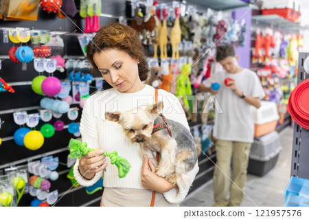 Woman chooses animal rope toys for cleaning teeth in pet store 121957576