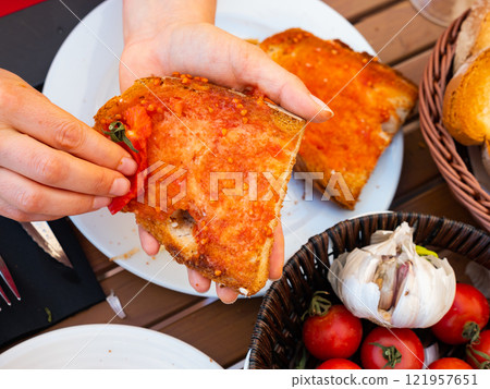Female hands rubbing toast with tomato while preparing Pan Con Tomate 121957651