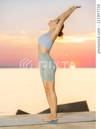 Near sea during sunset, girl performs Tiryaka Tadasana Near sea during sunset, girl performs Tiryaka Tadasana 121957726