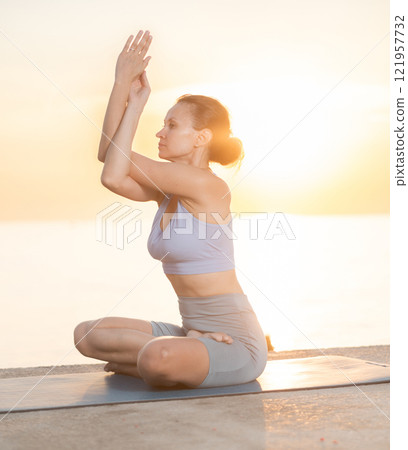 Near sea during sunset, girl performs variations of padmasana 121957732