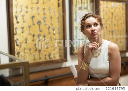 Interested woman looking at collection of medieval sculptures and objects in history museum 121957795
