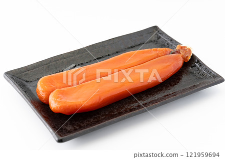 A whole bunch of dried mullet roe on a plate 121959694
