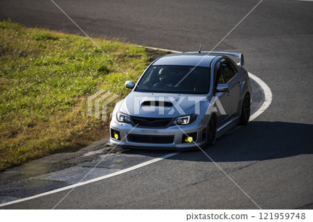 一輛銀色汽車在賽道上轉彎 一輛銀色汽車在賽道上轉彎 121959748