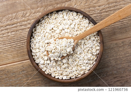 Overhead view of rolled oats on a plate and a wooden spoon on a wooden table 121960736