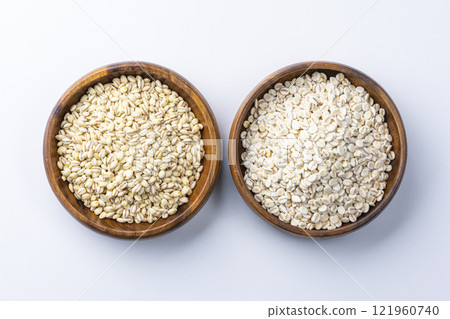Aerial view of barley and rolled barley served in a wooden bowl on a white background Aerial view of barley and rolled barley served in a wooden bowl on a white background 121960740