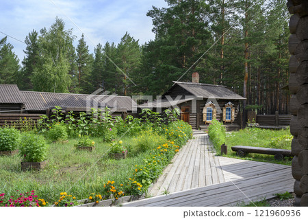 The restored courtyard of the 19th century manor with carved shutters on windows, log fence, garden 121960936