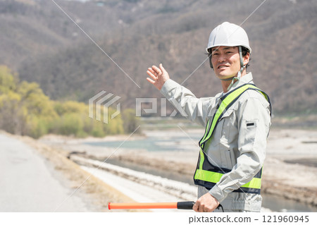 A male security guard directing traffic on the riverbank and embankment 121960945