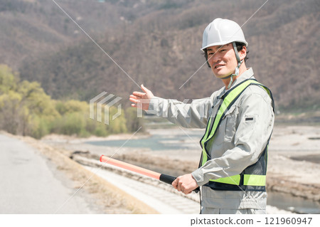 A male security guard directing traffic on the riverbank and embankment 121960947