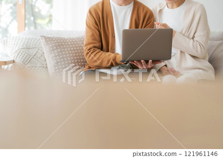 Part cut of a couple looking at a computer 121961146