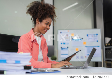 Businesswomen hand working with tablet and laptop computer with documents on office desk in modern office. Businesswomen hand working with tablet and laptop computer with documents on office desk in modern office. 121961452