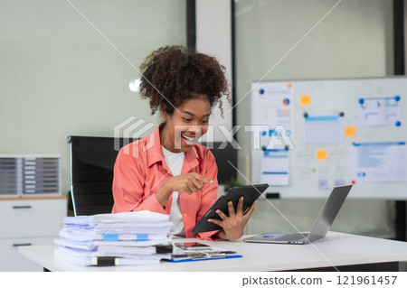 Overjoyed charming excited black woman business woman worker using tablet and laptop working in office, feeling happy. Overjoyed charming excited black woman business woman worker using tablet and laptop working in office, feeling happy. 121961457