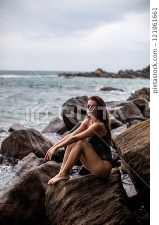 Serene Seaside Retreat A woman enjoying her time on a beautiful rocky shoreline by the ocean 121961661