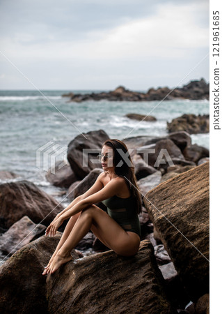Serene Seaside Retreat A woman enjoying her time on a beautiful rocky shoreline by the ocean Serene Seaside Retreat A woman enjoying her time on a beautiful rocky shoreline by the ocean 121961685