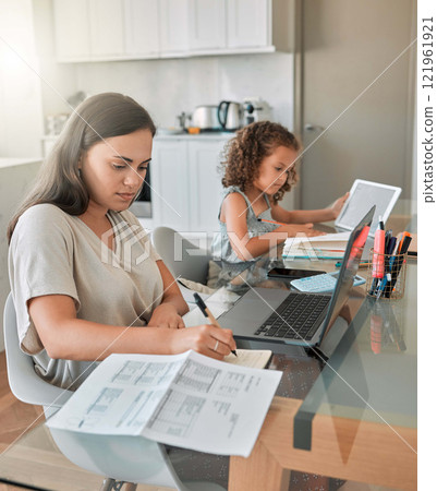Mother and daughter being productive with remote work and homework, multitasking at a kitchen table at home. Parent and child serious while paying bills and watching an online education programme 121961921