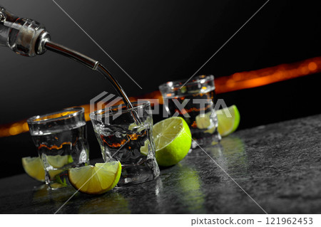 Strong alcoholic drink and lime slices on a dark background. Strong alcoholic drink and lime slices on a dark background. 121962453
