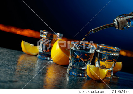 Vodka and lemon slices on a dark blue background. Vodka and lemon slices on a dark blue background. 121962454