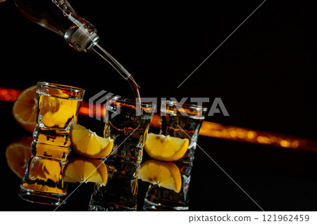 Vodka and lemon slices on a black background. Vodka and lemon slices on a black background. 121962459