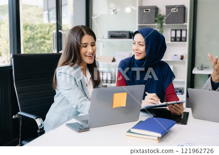 Two business workers talking on the smartphone and using laptop at office. 121962726