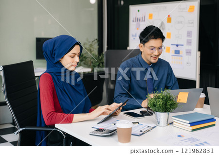 Two business workers talking on the smartphone and using laptop at office. 121962831