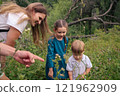 A joyful family happily discovers the enchanting beauty of nature in a vibrant, flowerfilled meadow area 121962909