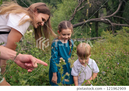A joyful family happily discovers the enchanting beauty of nature in a vibrant, flowerfilled meadow area 121962909