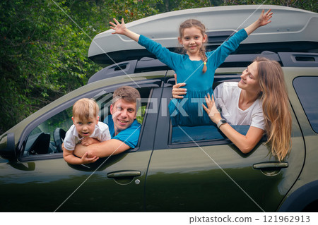 A joyful and cheerful family of four enjoying a funfilled outdoor trip together in their spacious SUV 121962913