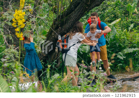 A family joyfully navigates through a lush green forest, sharing wonderful moments together in nature A family joyfully navigates through a lush green forest, sharing wonderful moments together in nature 121962915