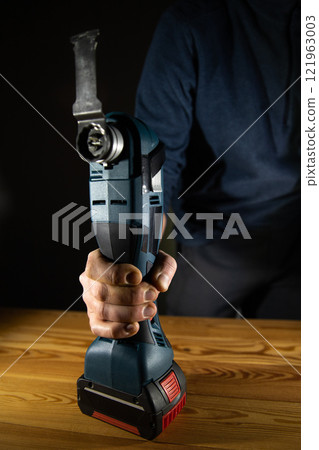 A person effectively using a reliable cordless power Multi-Cutter tool for various DIY projects and home repairs 121963003