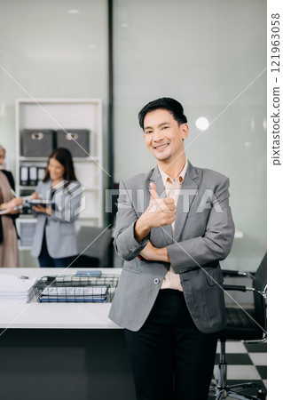 Young attractive Asian male office worker business Asian male office worker business suits smiling at camera in office . teamwork startup concept Young attractive Asian male office worker business Asian male office worker business suits smiling at camera in office . teamwork startup concept 121963058