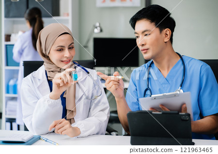 Doctor Talks With Professional Head Nurse or Surgeon, They Use Digital tablet Computer. Diverse Team of Health Care Specialists Discussing Test Result on desk 121963465