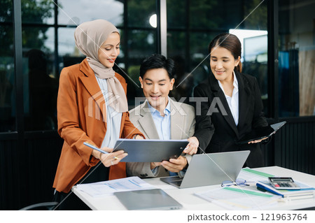 Asian businesspeople while collaborating on a new project.  using a laptop and tablet 121963764