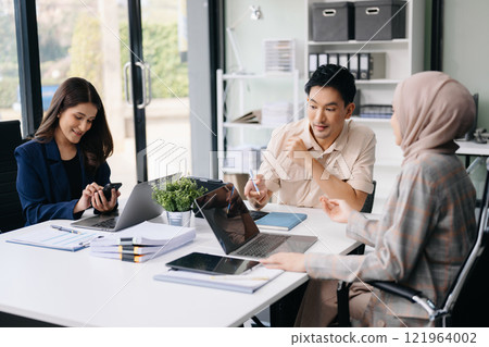 Happy businesspeople while collaborating on a new project in an office. Group of diverse businesspeople using a laptop and tablet 121964002