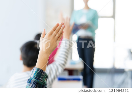 Image of elementary school students raising their hands in the classroom 121964251