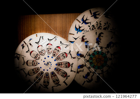 Intricate circular artwork featuring colorful figures dancing around a spiral design in a historical exhibit setting. The circular artwork showcases elegantly dressed figures in vibrant clothing, arra 121964277